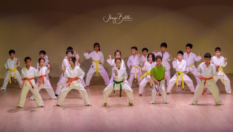 Kids in karate uniforms with red belts
