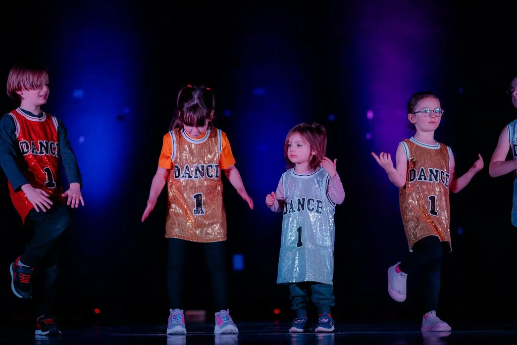 Kids performing on stage under blue lights